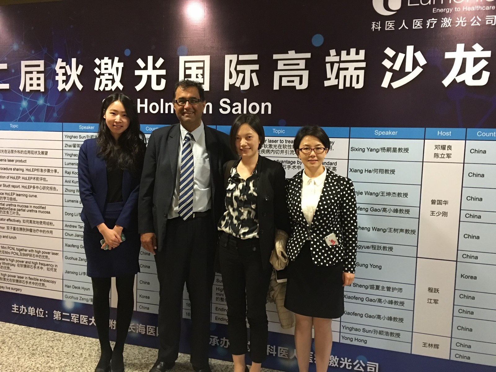 Dr Raji Kooner with colleagues in front of a HoLEP salon program display
